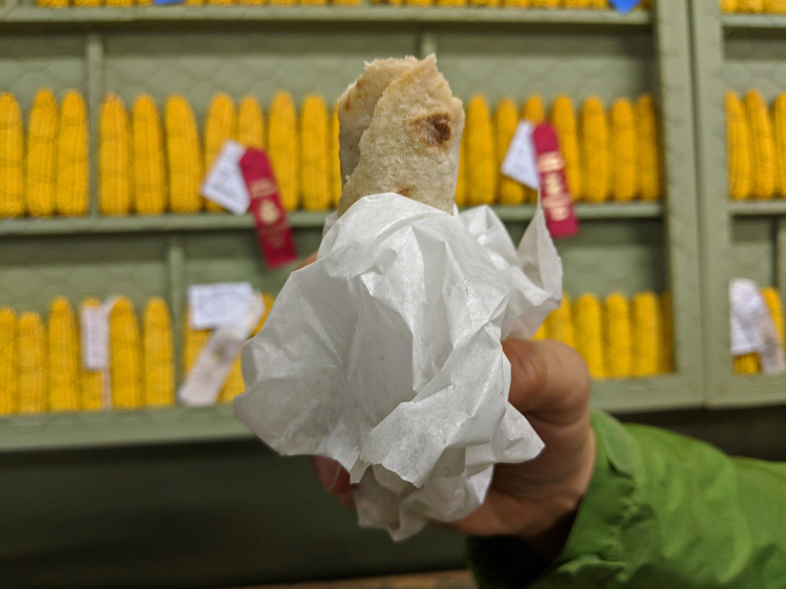 Lefse in hand with seed corn display in background